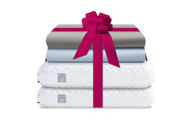 2 Cloud Pillows stacked on top of 2 Sheet sets tied with a ribbon