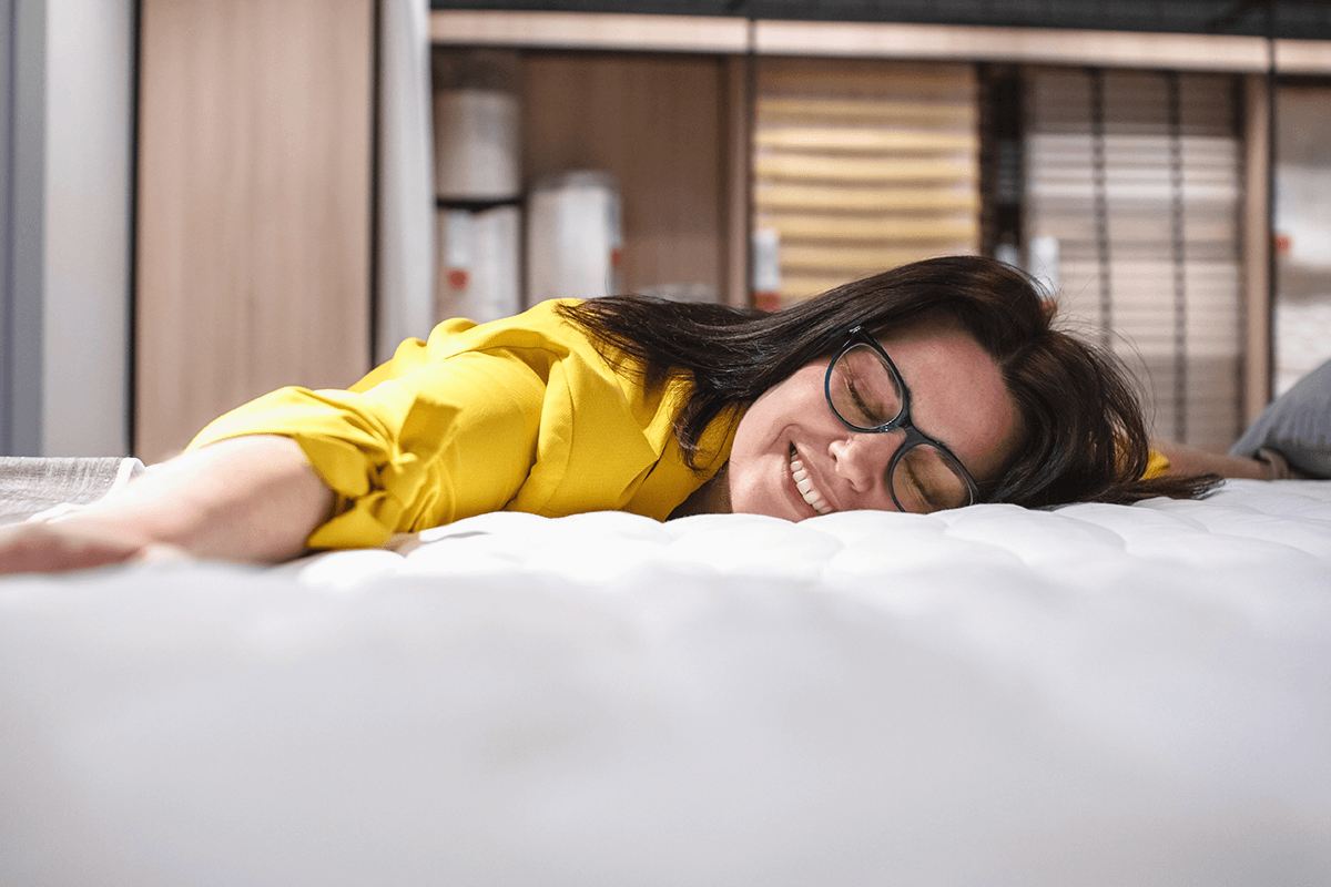 Woman joyfully testing a mattress in store