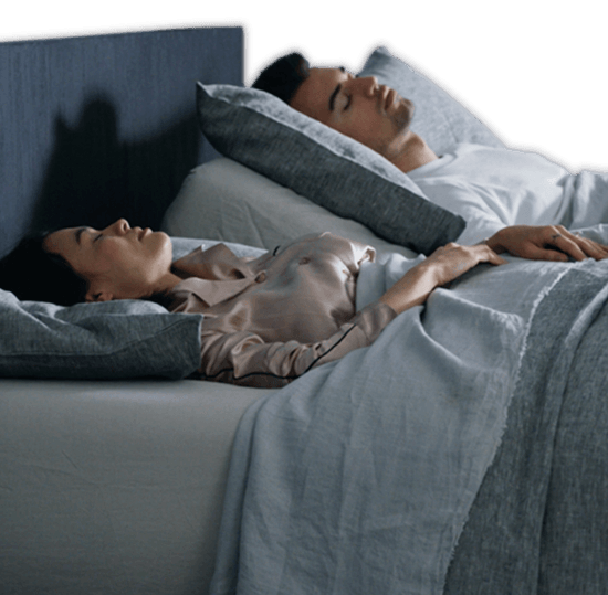 A couple sleeping with the man elevated using the automatic snore response feature.