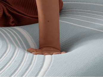 a hand pressing down into the mattress TEMPUR-Material