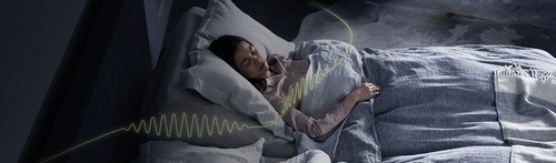 Woman sleeping in a bed with snore response technology