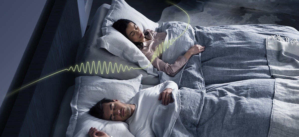 A couple sleeping with the woman slightly elevated using the automatic snore response feature